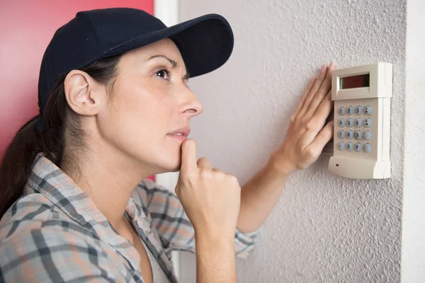 Denkende Technikerin stellt das Thermostat ein — Stockfoto