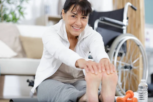 Gelukkig volwassen vrouw stretching op een mat — Stockfoto