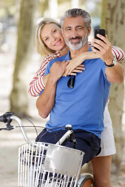 Casal com bicicletas tomando selfie no parque — Fotografia de Stock