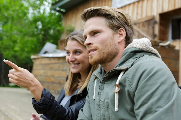 Een glimlachend paar houten huis achtergrond — Stockfoto