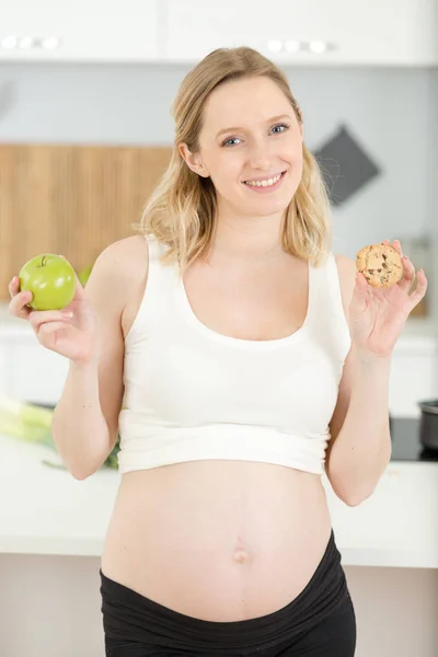 Kvinna som håller äpple och choklad kaka hemma — Stockfoto