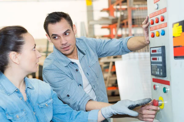 Ingenieur en leerling die in de fabriek aan de machine werken — Stockfoto