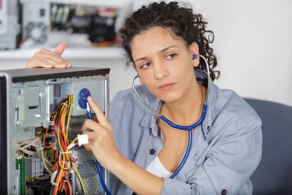 Женщина слушает компьютер через стетоскоп — стоковое фото