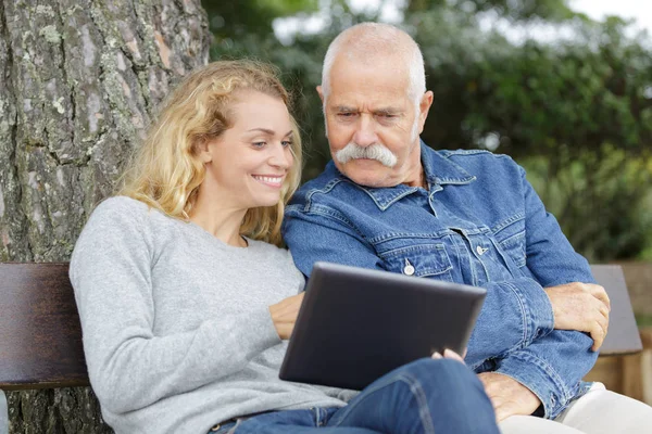 Filha com seu pai usando tablet no parque — Fotografia de Stock