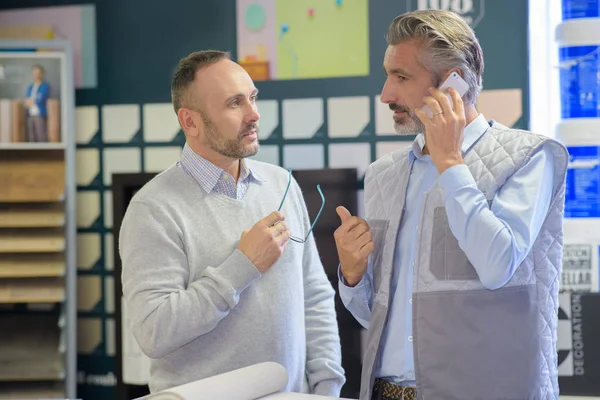 Manager praat aan de telefoon naast de werknemer — Stockfoto