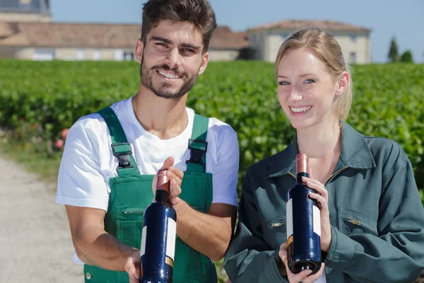 Viticultores felices sosteniendo botella de vino — Foto de Stock