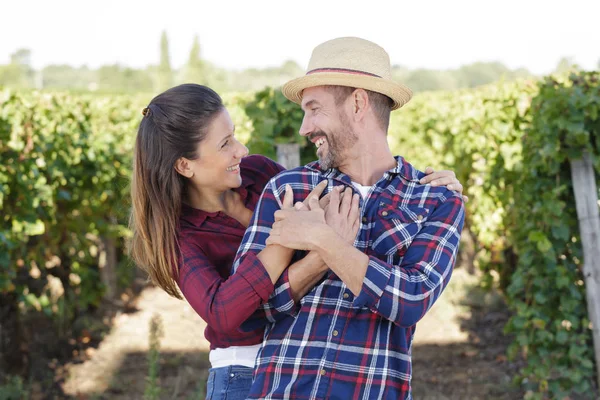 Casal de agricultores abraçando em vinhas — Fotografia de Stock