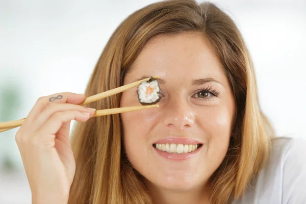 Usmívající se mladá žena drží sushi na oku — Stock fotografie