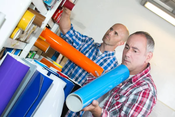 Ouvriers examinant des rouleaux de vinyle coloré — Photo