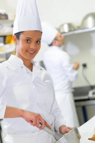 Mujer joven chef mezclando algo en el tazón — Foto de Stock