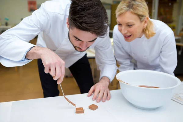 Confitero aprendiz preparando cuadrados de chocolate —  Fotos de Stock