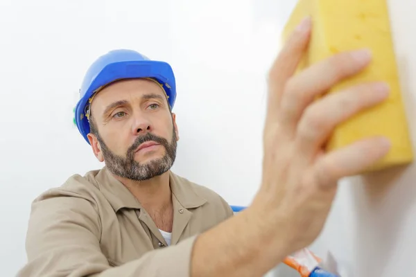 Lavoratore che tiene spugna uso per la pulizia dopo intonaco — Foto Stock