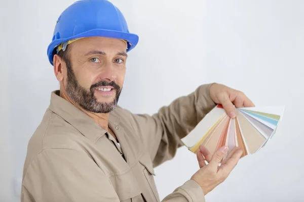 Pintor en ropa de trabajo azul celebración de muestras de color — Foto de Stock