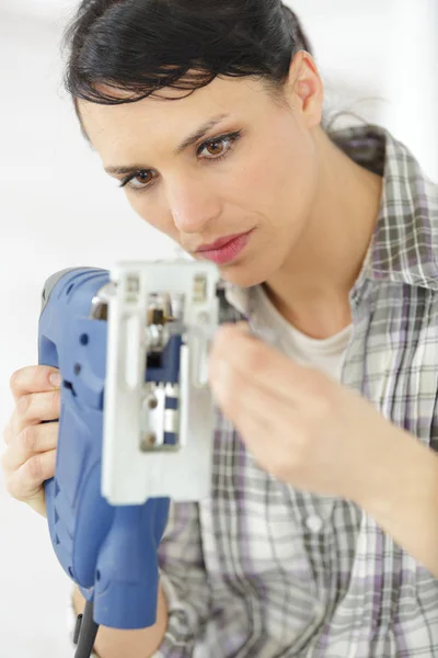 Carpintaria feminina profissional de meia-idade grave que fixa uma broca elétrica — Fotografia de Stock