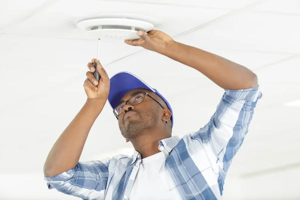 Mens montage veiligheidsmelder aan plafond — Stockfoto