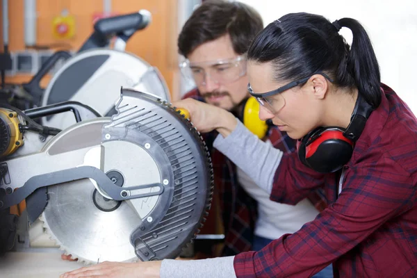 Carpenter and female apprentice working together in workshop — ストック写真