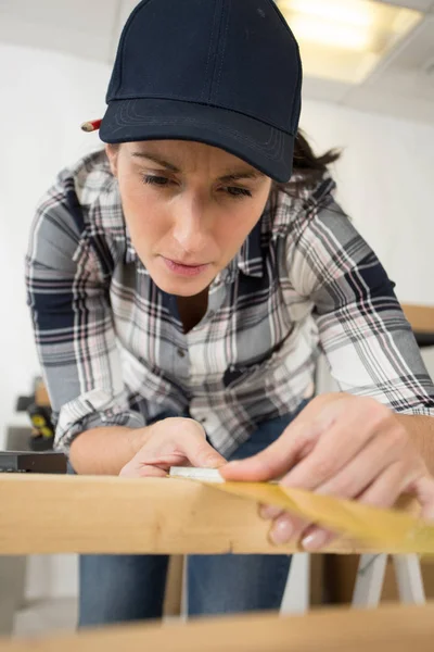 Femme mesurant une planche en bois — Photo