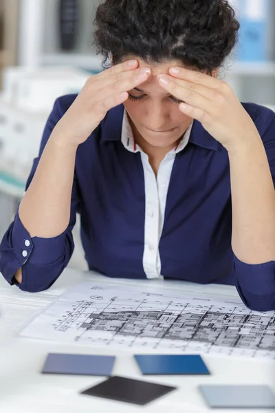 Zaniepokojona kobieta przegląda plany w biurze — Zdjęcie stockowe