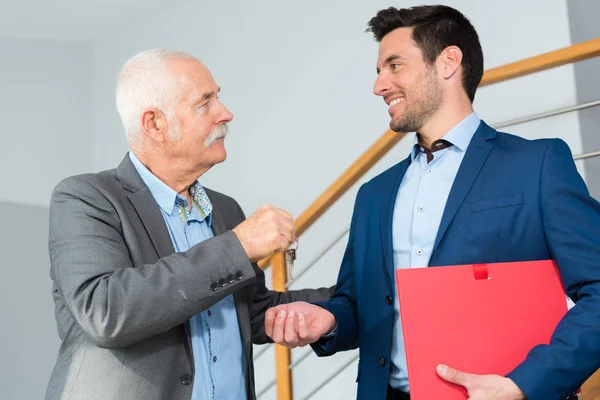 Starszy mężczyzna daje klucz młodszemu mężczyźnie — Zdjęcie stockowe
