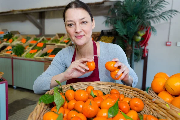 Portret van vrouwelijke kruidenier met clementines — Stockfoto