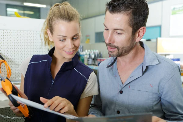 Operaio negozio di ferramenta con cliente guardando brochure — Foto Stock