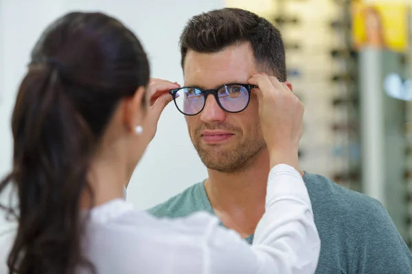 Man provar glasögon i optisk butik medan leende — Stockfoto