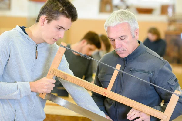 Homens jovens usando serra na classe woordwork — Fotografia de Stock