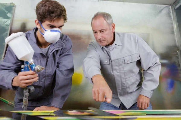 Ученик художника с воздушным пистолетом распыления краски на автомобиль — стоковое фото