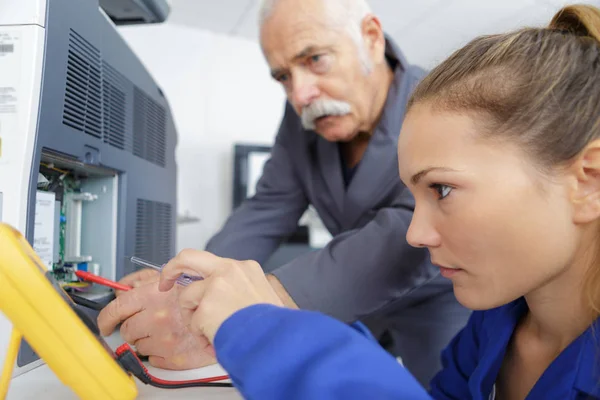 Jeune technicienne utilisant le multimètre sur l'appareil — Photo