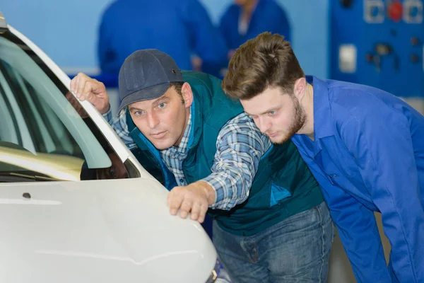 Mecânico com aprendiz verificando carroçaria do carro — Fotografia de Stock