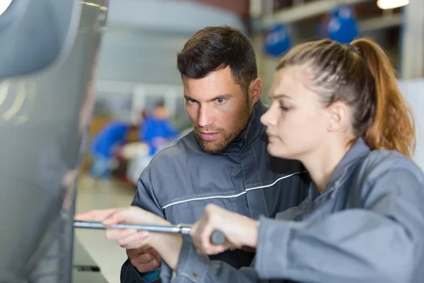 Monteur en vrouwelijke stagiair werken samen aan auto — Stockfoto