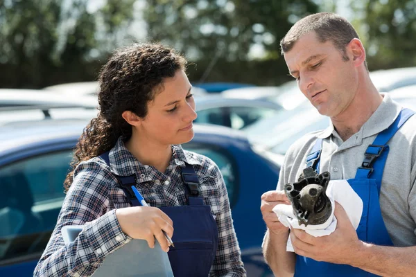 Mechanic and apprentice looking at automotive part — Stock Photo, Image