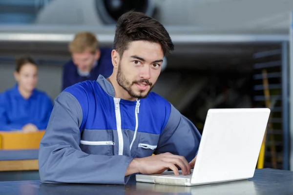 Portret van een jonge man in een overall met laptop — Stockfoto