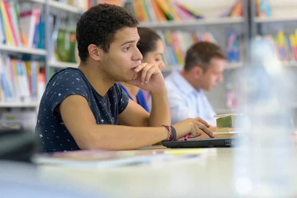 Estudante na biblioteca usando laptop — Fotografia de Stock