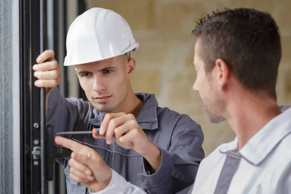 Two men installing window mount at construction site — ストック写真