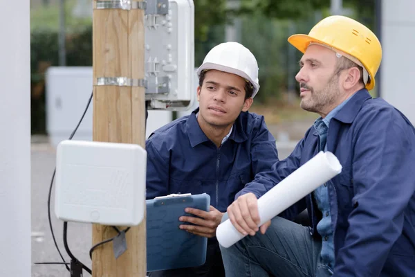 Foto van een elektrotechnicus die een post inspecteert — Stockfoto