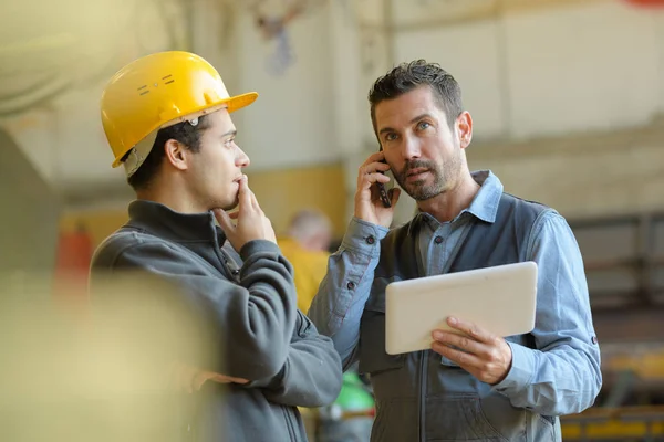 Männlicher Manager mit harter Mütze telefoniert — Stockfoto