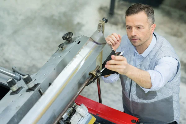 Travailleur vérifiant une machine d'impression — Photo