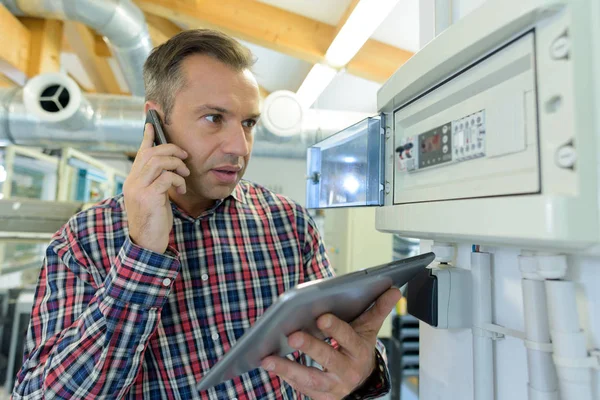 Serviceman on telephone by electronic control panel — Stock Photo, Image