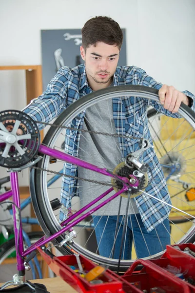 Homem de fixação roda de bicicleta na loja — Fotografia de Stock