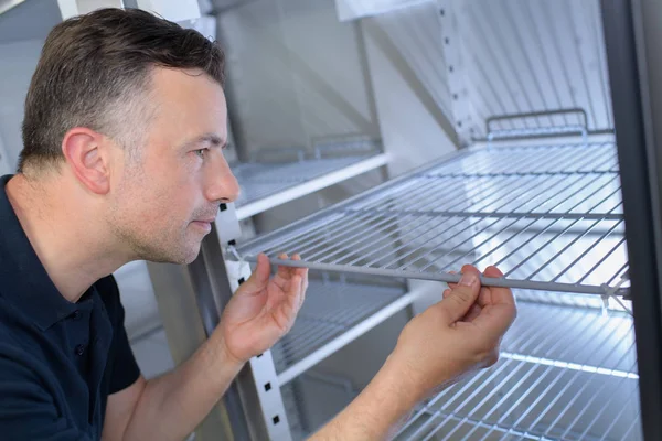 Homem que monta prateleira na geladeira — Fotografia de Stock