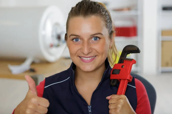 Vrouw bouwer houden moersleutel tonen duim omhoog — Stockfoto