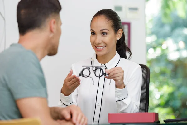 Woman showing glasses to optician at optics store — Stock Photo, Image