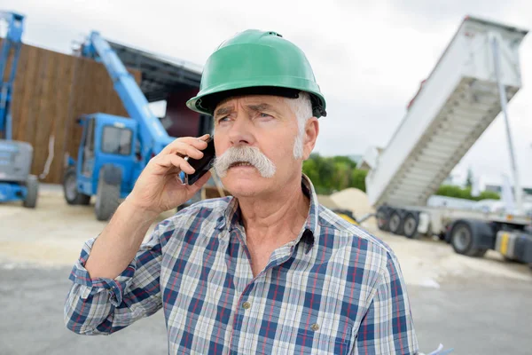 Senior man använder smartphone på byggarbetsplatsen — Stockfoto