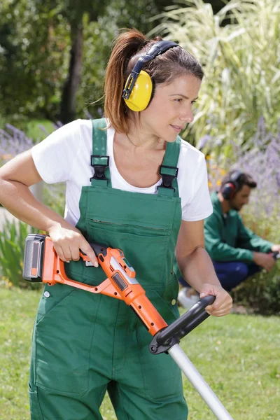 Jardinero femenino usando una cortadora de césped — Foto de Stock