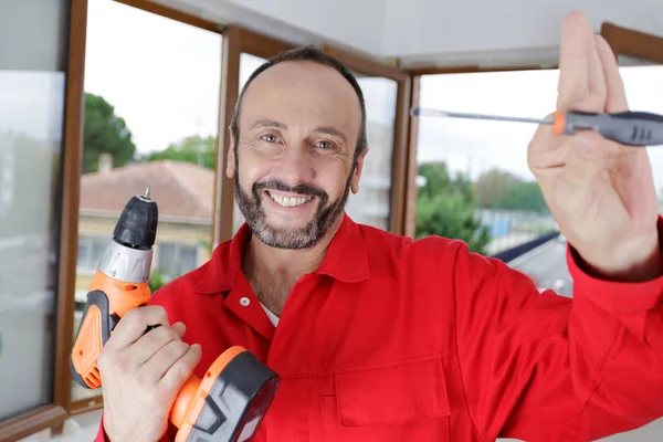 Felice uomo in possesso di un trapano e un cacciavite — Foto Stock