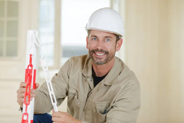 Dojrzały pracownik zakładający czerwony i biały łańcuch bezpieczeństwa w paski — Zdjęcie stockowe