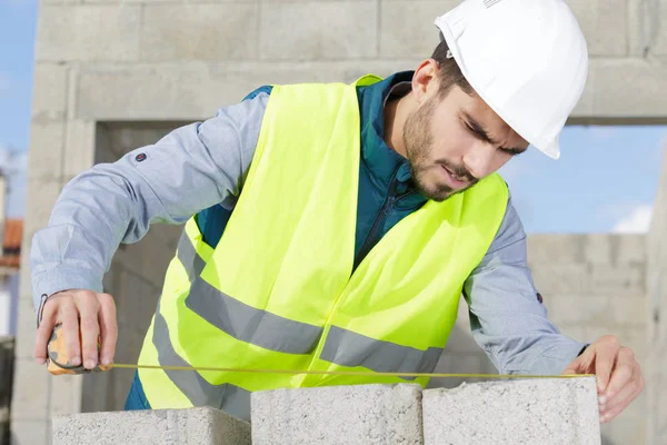 Construtor macho branco feliz na frente da janela com fita métrica — Fotografia de Stock