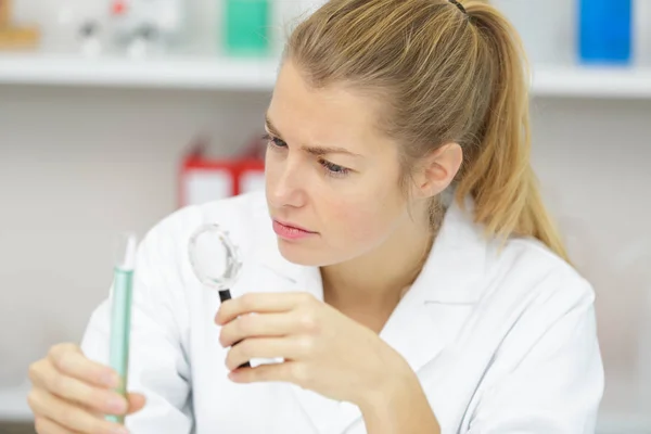 Женщина-врач держит пробирку в лаборатории — стоковое фото