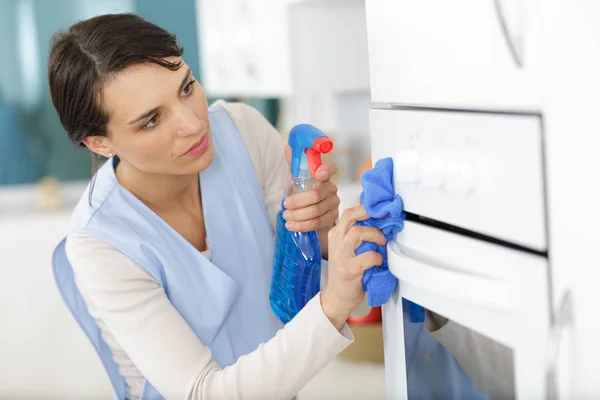 Housemaid cleaning oven in kitchen — 스톡 사진